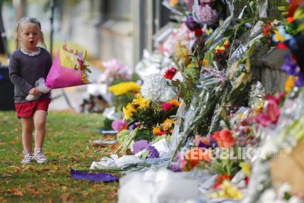 A girl walk to lay flowers on a wall at the Botanical Gardens in Christchurch, New Zealand, Sunday, March 17, 2019. New Zealand's stricken residents reached out to Muslims in their neighborhoods and around the country on Saturday, in a fierce determination to show kindness to a community in pain as a 28-year-old white supremacist stood silently before a judge, accused in mass shootings at two mosques that left dozens of people dead. (AP Photo/Vincent Thian)