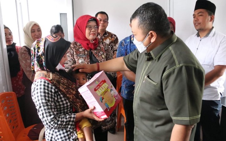 Bupati Tapsel Dolly Pasaribu saat memberikan makanan tambahan pada seorang ibu. (Dok)