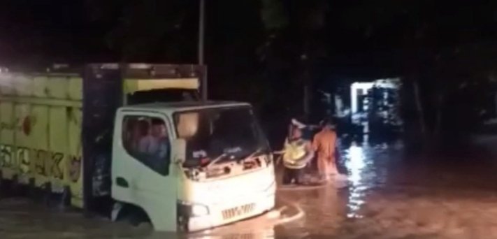 Personal Polres Labuhanbatu saat di lokasi banjir sedang membantu kendaraan yang terjebak banjir. (IST)