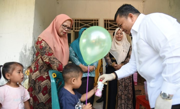 Bupati Tapsel Dolly Pasaribu memberi makanan tambahan pada para balita yang di Sub Pin Polio. (IST)