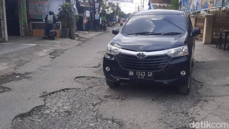 Mobil melintas di Jalan Pimpinan Medan yang kondisinya rusak.