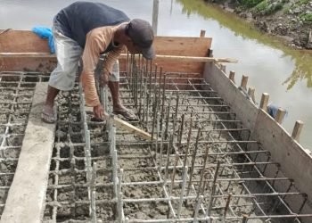 Pekerja sedang melakukan pemadatan pengecoran  dengan menggunakan balok. (IST)