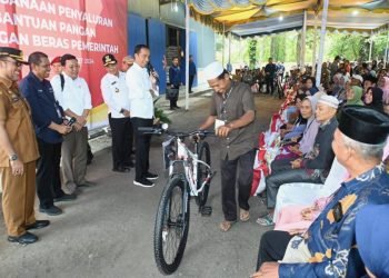 Penjabat (Pj) Gubernur Sumatera Utara (Sumut) Hassanudin  mendampingi Presiden RI Joko Widodo (Jokowi) menyalurkan bantuan pangan cadangan beras pemerintah di GDT Hutalombang, Padanglawas, Jumat (15/3).  (DISKOMINFO SUMUT)