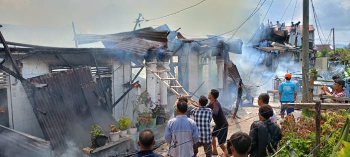 Petugas damkar dibantu warga saat berusaha memadamkan api.