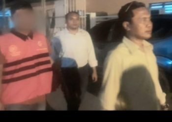 Tersangka AN saat disamping Kajari Padangsidimpuan menuju mobil tahanan di Kantor Kejari Padangsidimpuan, Senin malam (1/7/2024).