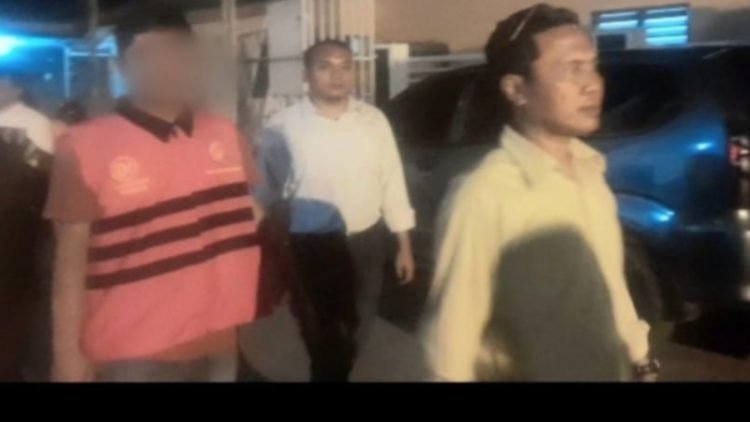 Tersangka AN saat disamping Kajari Padangsidimpuan menuju mobil tahanan di Kantor Kejari Padangsidimpuan, Senin malam (1/7/2024).