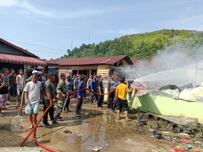 Warga dan petugas Damkar berupaya memadamkan api.