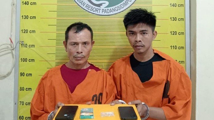 Kedua pelaku saat diamankan di kantor polisi.