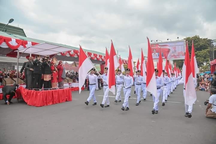Pj.Wali Kota Padangsidimpuan H.Timur Tumanghor dan istri berpakaian adat Tabagsel sedang memberi penghormatan pada barisan deville merah putih di HUT ke-79 RI. (IST)