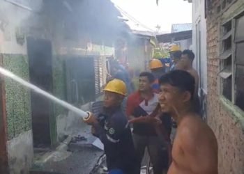 Petugas memadamkan api di rumah kontrakan yang terbakar di Kisaran.