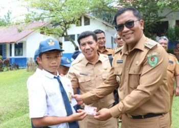 Plt. Bupati Tapsel Rasyid Assaf Dongoran saat membagikan KIA pada SMPN 4, Kelurahan Batang Tura Sirumambe, Kecamatan Angkola Timur, Senin (30/9). (IST)