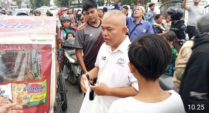 Ketua IMO Sumut saat membagikan takjil kepada pengendara yang melintas di depan  Taman Makam Pahlawan. (IST)