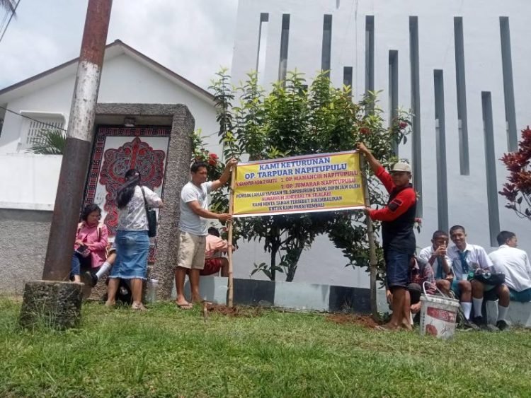 Keturunan Tarpuar Napitupulu pasang spanduk permintaan tanahnya untuk dikembalikan Yayasan TB Soposurung, Balige, Rabu (9/4/2025). 