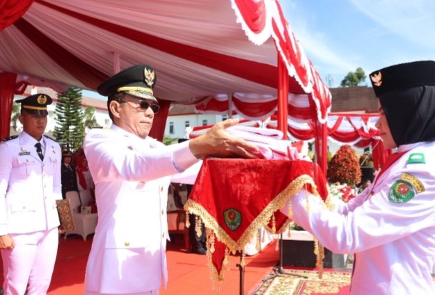 Bupati Tapsel Gus Irawan Pasaribu menyerahkan bendera Merah putih pada Jogina Juwita Pulungan pembawa baki untuk dikibarkan pada HUT ke-80 RI Tapsel. (IST)