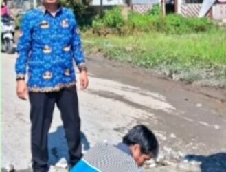 Camat Uluan Juni Hanmas Butarbutar sedang mengawasi perbaikan jalan. (IST)