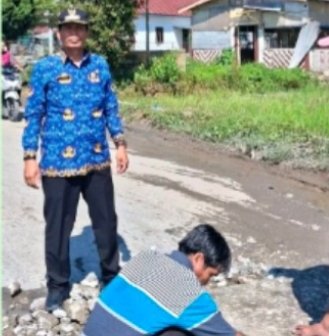 Camat Uluan Juni Hanmas Butarbutar sedang mengawasi perbaikan jalan. (IST)