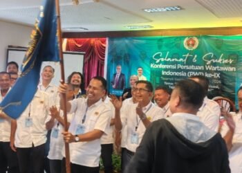 Ketua PWI Tabagsel yang baru Julpan Tambunan mengibarkan bendera petaka PWI usai dikukuhkan. (IST)