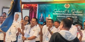 Ketua PWI Tabagsel yang baru Julpan Tambunan mengibarkan bendera petaka PWI usai dikukuhkan. (IST)