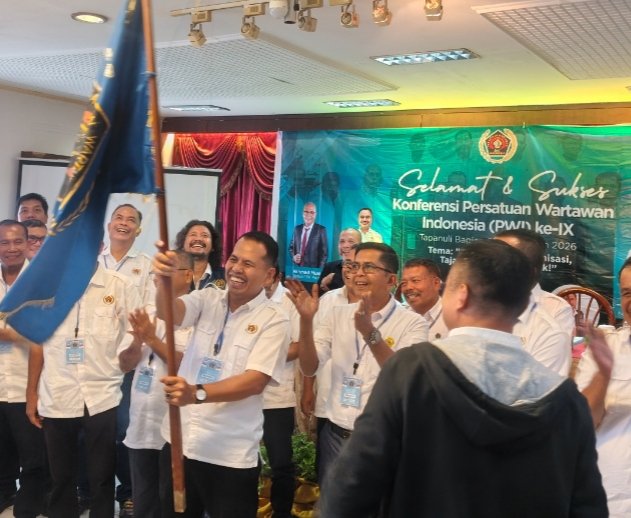 Ketua PWI Tabagsel yang baru Julpan Tambunan mengibarkan bendera petaka PWI usai dikukuhkan. (IST)